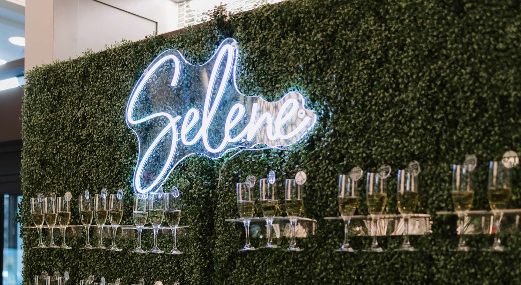 bright lobby wall with neon Selene sign and glasses of wine